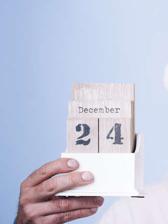 Man holding calendar with 24 december date in hands, on dark blue. Christmas eve time.