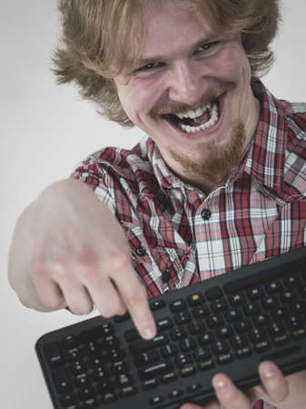 Nerd geek young adult man playing video games holding computer keyboard. Being addicted to gaming concept.の写真素材
