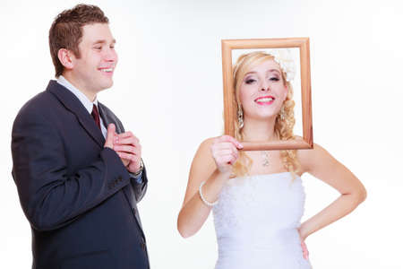 Wedding day, negative relationship concept. Groom and bride holding, posing with empty photo frame having bad argument.の写真素材