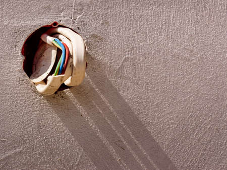 Colorful cables wires sticking out of grey concrete wall. Details during house renovations.