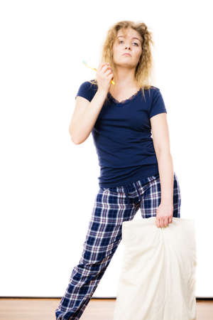 Sleepy woman wearing blue pajamas holding pillow, sleep outfit blue tshirt and checked trousersの写真素材