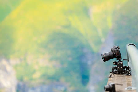 Modern professional camera, outdoor photography in wildlife. Mountains background. Travel, tourism and holiday concept.の写真素材