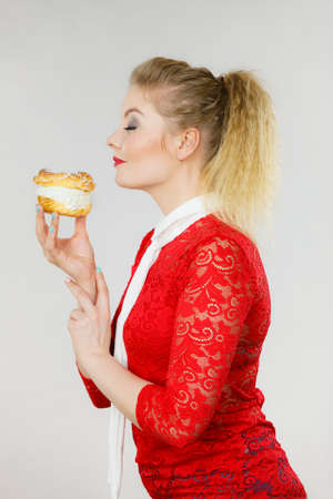 Sweet food and happiness concept. Woman holding yummy choux puff cake with whipped cream.の写真素材