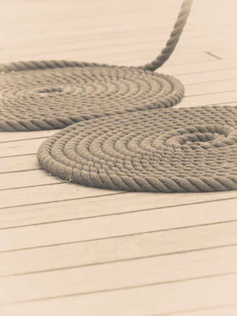 Old nautical objects concept. Circle rounded antique chest rope coil on wooden floor.