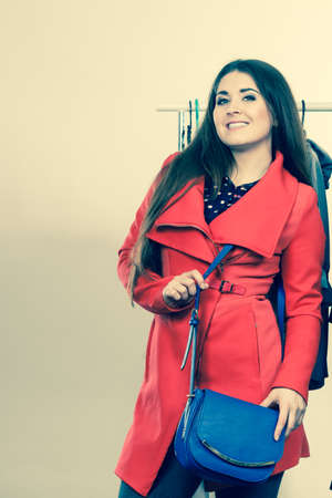 Happy young woman during shopping time trying on red jacket for perfect fashionable outfit.の写真素材