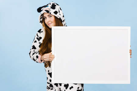 Smiling teenage girl in funny nightclothes, pajamas cartoon style with blank empty banner board. Advertisement copyspace.の写真素材
