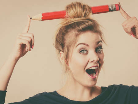 Charming happy blonde woman having big pencil in hair having fun, education ideas.の写真素材