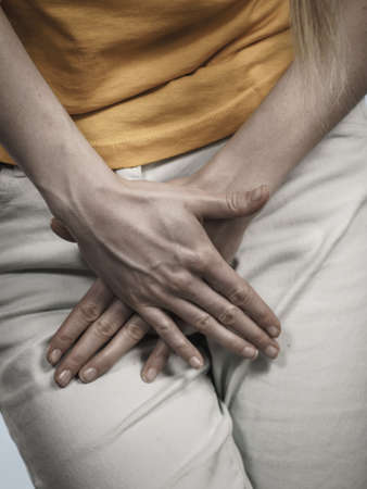 Closeup young sick woman with hands holding pressing her crotch lower abdomen. Medical or gynecological problems, healthcare conceptの写真素材