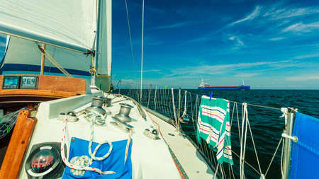 Yachting on sail boat during sunny summer weather on calm blue sea water. Sporty transportation...