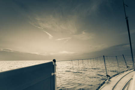 Yachting on sail boat during sunny summer weather on calm sea water. Sporty transportation concept.