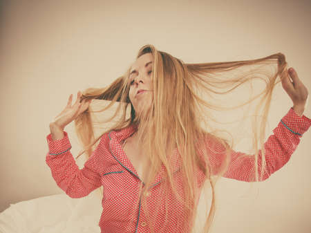 Awaken morning young blonde woman wearing pink pajamas stretching body after sleepingの写真素材