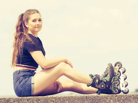 Happy joyful young woman wearing roller skates relaxing after long ride. Female being sporty having...