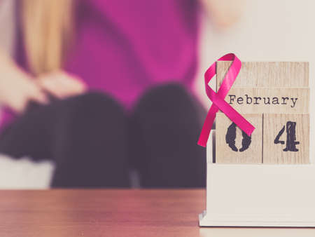 Woman and calendar, it is 4 february world breast cancer day, date with pink awareness ribbon. Healthcare and medicine concept.の写真素材