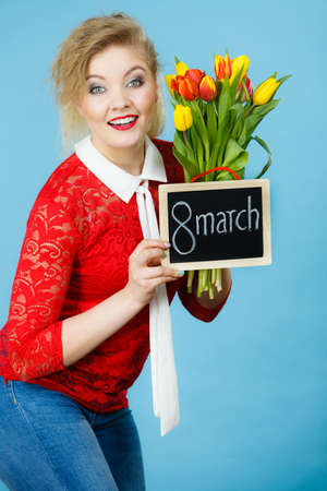 International women day. Beautiful woman blonde hair fashion make up holding red yellow tulips and...