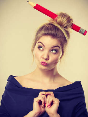 Charming thinking blonde woman having big pencil in hair having something on her mind, education ideas.の写真素材