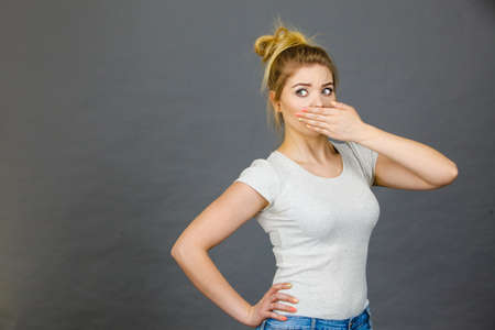 Woman covering her mouth with hand. Seeing something shocking, surprised and speechless face expression.の写真素材