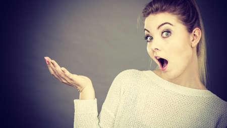 Confused young blonde woman gesturing with hands. Confusion face expressions concept. Studio shot on grey background.の写真素材