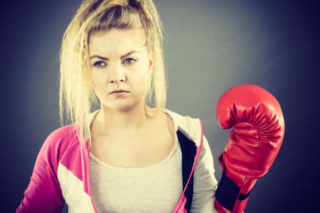 Sporty woman wearing red boxing gloves, fighting. Studio shot on dark background.の写真素材