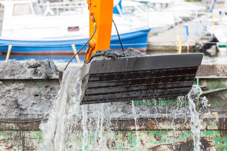 Excavator shovel digging in sand from water. Building construction, industrial objects concept.の写真素材