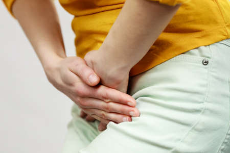 Part of body young sick woman with hands holding pressing her crotch lower abdomen. Medical or...