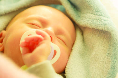 Infant care, beauty of childhood concept. Little newborn baby sleeping calmly in bed with teat in...