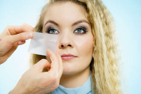 Professional artist fixing fashion model make up using oil blotting tissues. Cosmetic objects,...