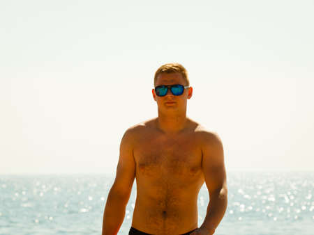 Summertime joy, summer recreation outside concept. Young sporty man spending vacation on beach near seaの写真素材