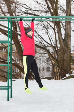 Workout in public park. Woman wearing warm sportswear urban street training exercising outside...