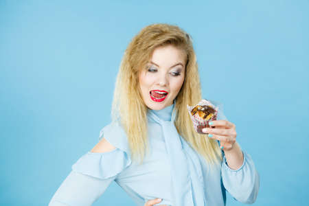 Sweet food sugar make us happy. Attractive blonde woman holds yummy chocolate cupcake in hand, open...