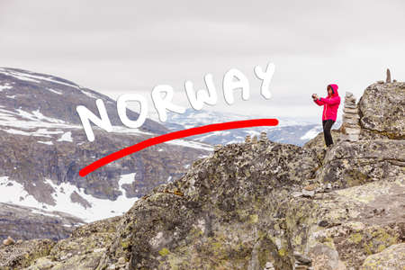 Tourism vacation and travel. Female tourist taking photo with camera, enjoying mountains landscape from Dalsnibba viewpoint, Norway Scandinavia.の写真素材