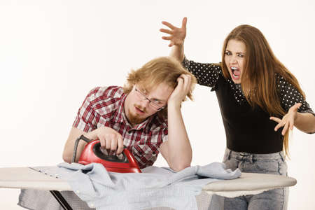 Woman trying to convince his man to do ironing, husband being bored and tired. Household domestic life problems.の写真素材