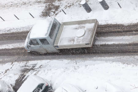 Bad weather conditions. Car on road covered with snow during winter time. High angle view from top.の写真素材