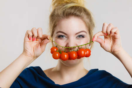 Organic vegetables and food concept. Happy positive smiling woman holding fresh cherry tomatoesの写真素材