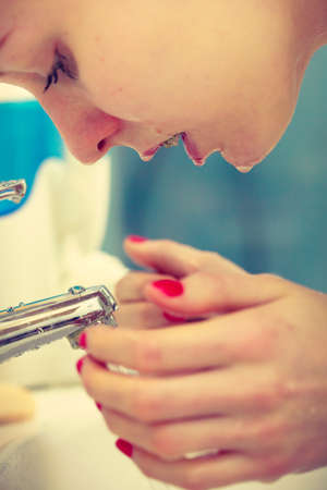 Woman cleaning washing her face with clean water in bathroom. Girl taking care of her complexion. Morning hygiene. Skincare treatment.の写真素材