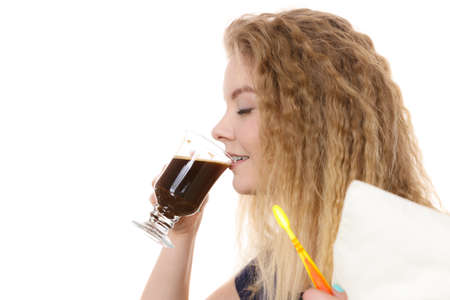 Funny woman holding black coffee and toothbrush being late. Getting morning energy, hurry up before going to work.の写真素材