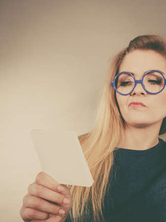 Thinking business woman wearing eyeglasses holding sticky note, looking at problem solution.の写真素材