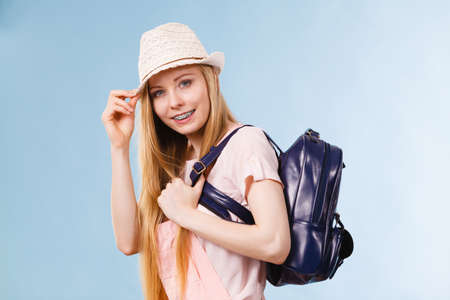 Happy young blonde teenage girl going to school or college wearing backpack.の写真素材