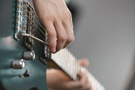 Close up of man playing on electric guitar during gig or at music studio. Musical instruments,...