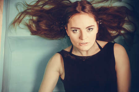 Portrait of sexy seductive woman wearing black dress in swimming pool water. Young attractive alluring girl floating. Top view.の写真素材