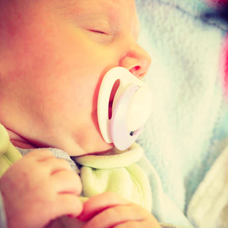 Infant care, beauty of childhood concept. Little newborn baby sleeping calmly in bed with teat in...