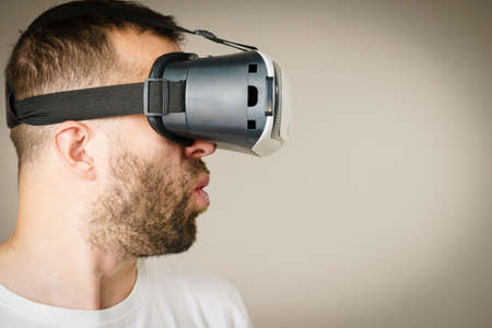 Adult short bearded guy exploring virtual reality wearing VR goggles being into technology. Studio...
