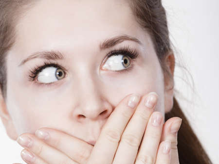 Shock face expressions concept. Closeup of shocked amazed woman covering mouth with hands