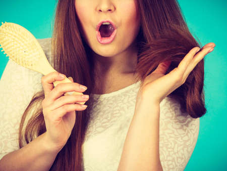 Haircare and morning hairstyling concept. Shocked amazed with wide open mouth woman holding hair...