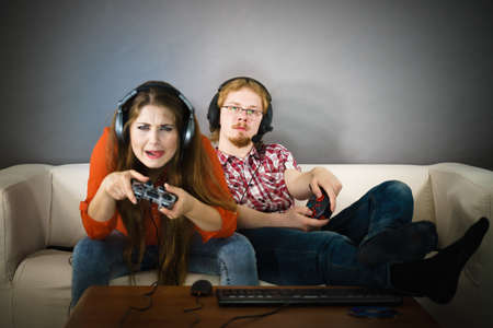Happy couple enjoying leisure time by playing video games together. Studio shot