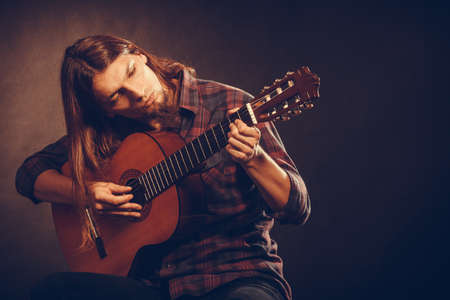 Hobby passion concept. Guitarist is playing the guitar. Long haired performer and his instrument.の写真素材