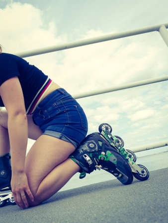 Unrecognizable woman putting on roller skates. Female being sporty having fun during summer in cityの写真素材