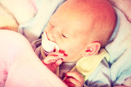 Infant care, beauty of childhood concept. Little newborn baby sleeping calmly in bed with teat in mouth.の写真素材