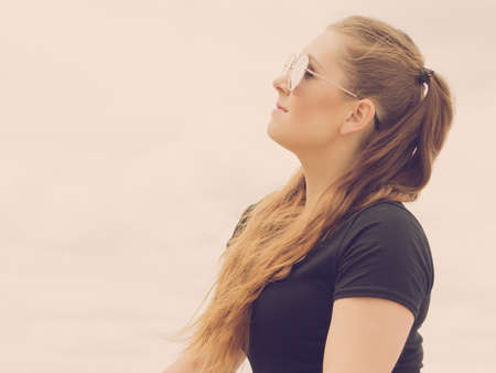 Young beautiful teenage woman spending her leisure time outside relaxing during summertime warm weather enjoying herself.の写真素材