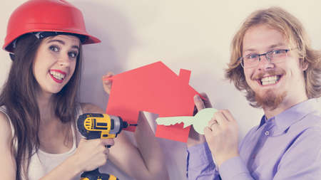 Man and woman holding house object model and drill about to do home renovationの写真素材