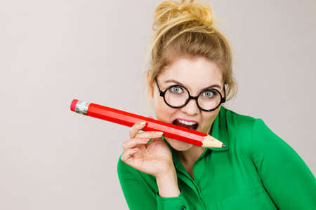 Funny crazy business woman wearing eyeglasses biting pencil. Studio shot on grey background.の写真素材